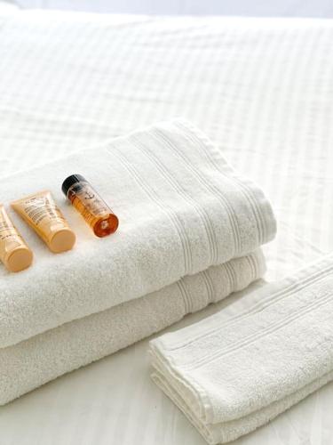 - une pile de serviettes et une bouteille de médicament sur le lit dans l'établissement Le St Laurent - Bord de Saône, à Chalon-sur-Saône