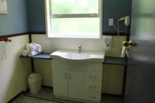 a bathroom with a sink and a window at Fairy Springs Motel in Rotorua