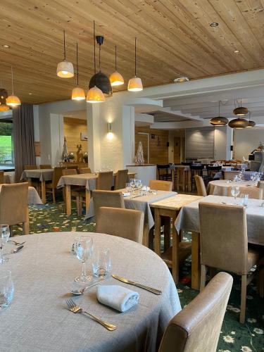 une salle à manger avec des tables blanches, des chaises et des lumières dans l'établissement Hôtel et appart'hôtel de l'Hermitage, à Thônes