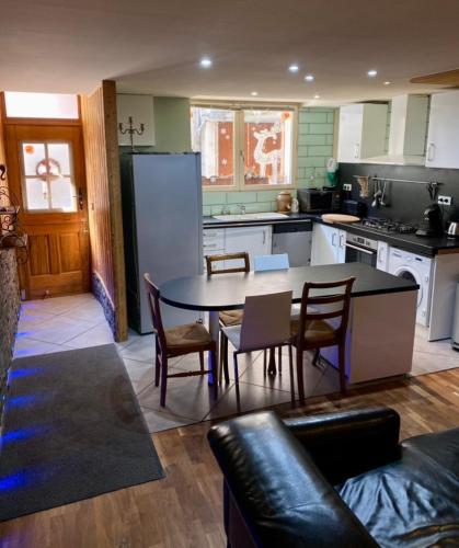 une cuisine avec une table, des chaises et un réfrigérateur dans l'établissement Maison ambiance chalet, au Bourg-dʼOisans
