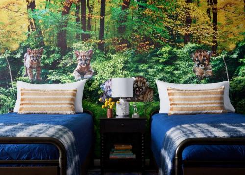 two beds in a bedroom with a mural of tigers at Graduate by Hilton State College in State College