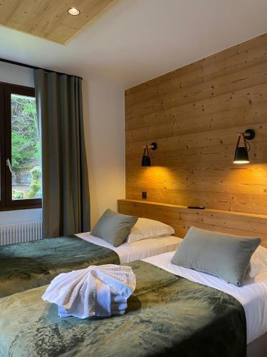 deux lits dans une chambre aux murs en bois dans l'établissement Hôtel et appart'hôtel de l'Hermitage, à Thônes