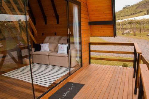 a porch of a wooden cabin with a couch at Cabanas Refúgio do Vale in Bento Gonçalves