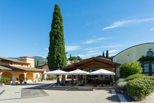 a building with umbrellas and a tree in a courtyard at Agriturismo Valentina Cubi in Fumane