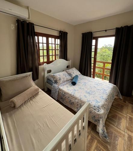 a bedroom with two beds and a balcony at Encanto Acomodações in Guarda do Embaú
