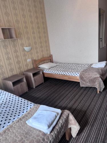 a hotel room with two beds and two tables at Motel Kurortnyy & SPA in Shklo