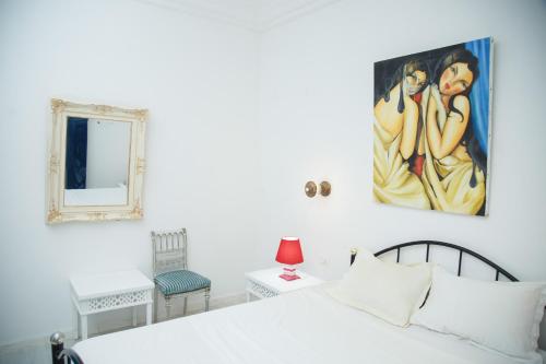 a bedroom with a white bed and a painting on the wall at Dar Amazigh in Tozeur
