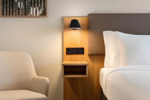 a bedroom with a bed and a chair and a lamp at Holiday Inn Beja by IHG in Beja