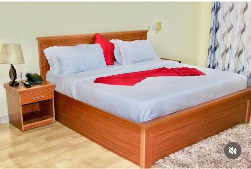 a bedroom with a large wooden bed with red pillows at Royal Village Dodoma in Dodoma