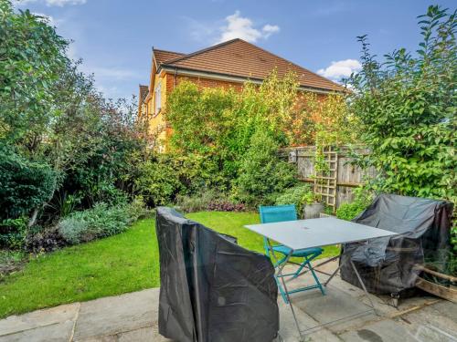 a patio with a table and chairs in a garden at Pass the Keys Spacious Family Oasis Explore with Ease in Leatherhead