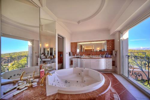 une grande salle de bain avec une baignoire et une grande fenêtre dans l'établissement Ref PRESTIGE by Palmes d Or Properties, à Mougins