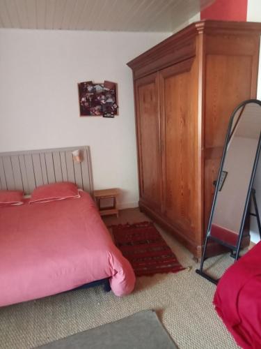 a bedroom with a pink bed and a wooden cabinet at Le Plessis renard in Haute-Goulaine