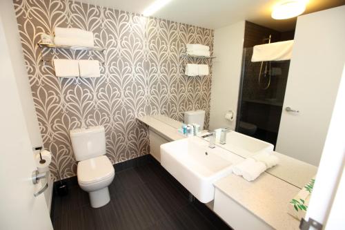 a bathroom with a toilet and a sink at Novotel New Plymouth Taranaki in New Plymouth