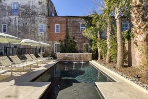 una piscina di fronte a un edificio in mattoni con palme di Bed&Breakfast Veranda King Suite - Walk to King a Charleston