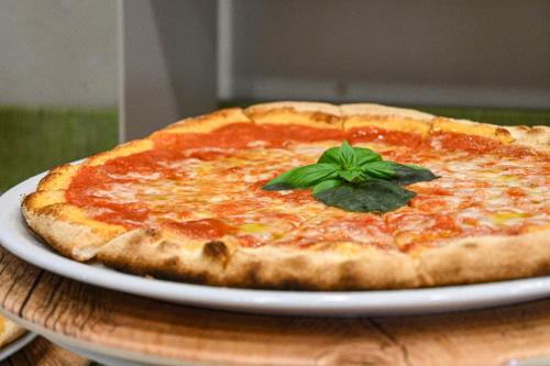 a pizza sitting on a white plate on a table at CSA Hotel Beach & Park in Marina di Bibbona
