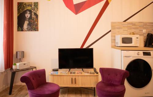 - un salon avec 2 chaises violettes et une télévision dans l'établissement La maison des artistes plein centre familiale, à Boulogne-sur-Mer
