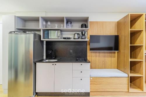 a kitchen with a refrigerator and a tv at RUP - Studios Equipados em Prédio com Piscina in Blumenau