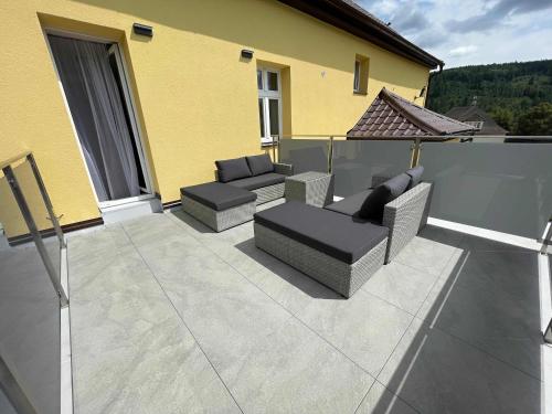 a patio with couches and chairs on a balcony at Apartmány U Bernharda in Vítkov