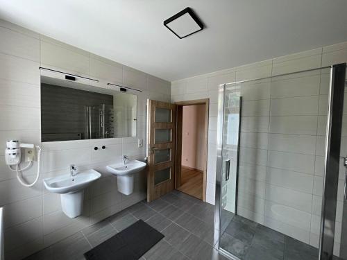 a bathroom with two sinks and a shower at Apartmány U Bernharda in Vítkov