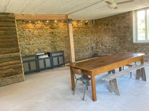 a wooden table in a room with a brick wall at Gîte Domaine du Berret 8 pers in Bully