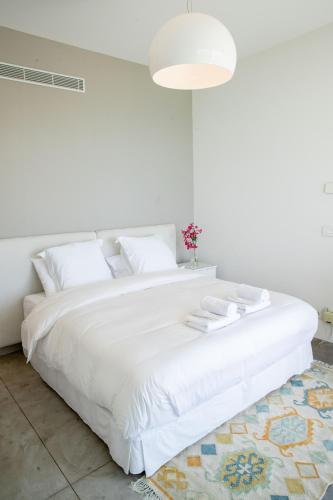 a white bedroom with a large white bed with a rug at Zita Fidar in Al Fīdār