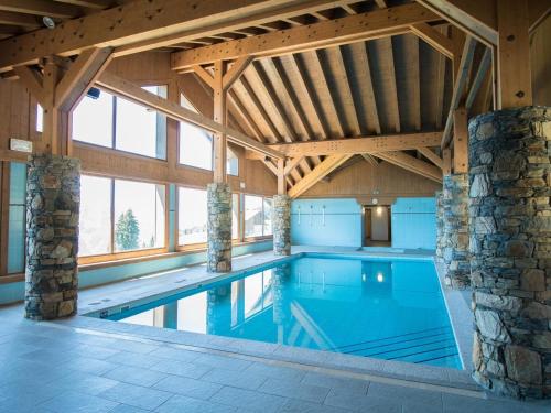 une grande piscine intérieure avec un plafond en bois dans l'établissement Appartement lumineux 8 pers avec piscine et parking près des pistes à Villard-sur-Doron - FR-1-293-363, à Villard-sur-Doron