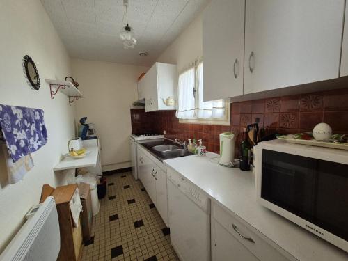 a kitchen with white cabinets and a sink at Le Devallon in Saint-Jean-de-Monts