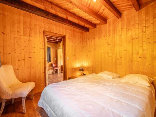 - une chambre avec des murs en bois, un lit et une chaise dans l'établissement Chalet cosy à La Clusaz, 9 pers, 4 chambres, wifi, proche pistes - FR-1-437-103, à La Clusaz
