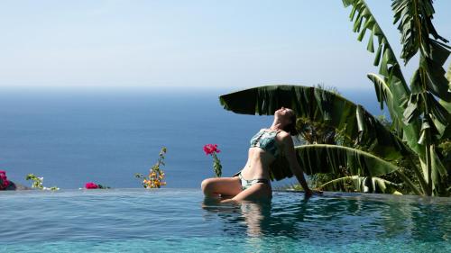 a woman sitting in the water in a swimming pool at Villas Bukit Lipah in Amed