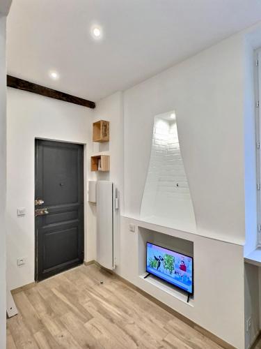 un salon avec une télévision à écran plat et une porte noire dans l'établissement WonderHost, joli studio rénové vers boulevard des Pyrénées, à Pau