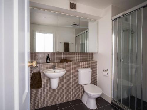 a bathroom with a toilet and a sink and a mirror at Degraves Della Casa- In the Heart of Melbourne CBD in Melbourne