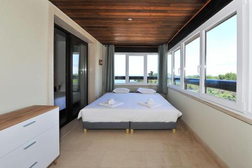 a bedroom with a bed in a room with windows at Amazing Sea View in Cascais