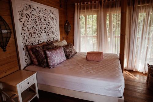 a bedroom with a bed with white sheets and windows at Villas Bukit Lipah in Amed