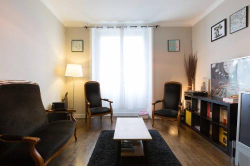 un salon avec deux chaises et une télévision dans l'établissement Flamboyant Lutèce - Élégance Parisienne au Cœur de la Ville, à Paris