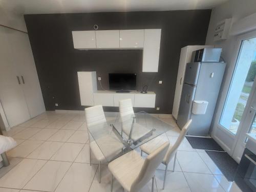 une cuisine avec une table en verre et des chaises blanches dans l'établissement Studio meublé avec cuisine, à Saint-Alban-du-Rhône