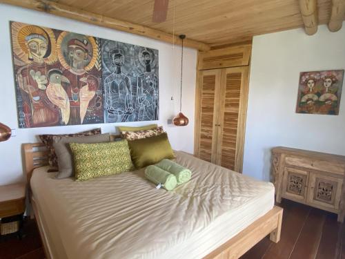 a bed in a room with a painting on the wall at Villas Bukit Lipah in Amed