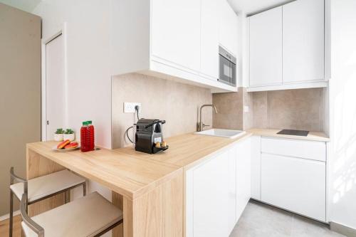 une cuisine avec des armoires blanches et un comptoir en bois dans l'établissement Studio au centre de Paris - Musée Grévin - II, à Paris