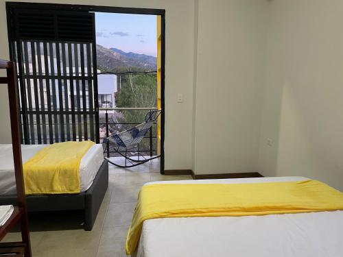 een slaapkamer met 2 bedden en een balkon met een stoel bij Hospedaje El Caminante CAPI in Capitanejo