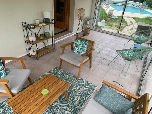 un patio avec une table et des chaises et une piscine dans l'établissement Gîte 3 étoiles les Gourlines avec balneo, véranda, piscine et garage, à Avermes