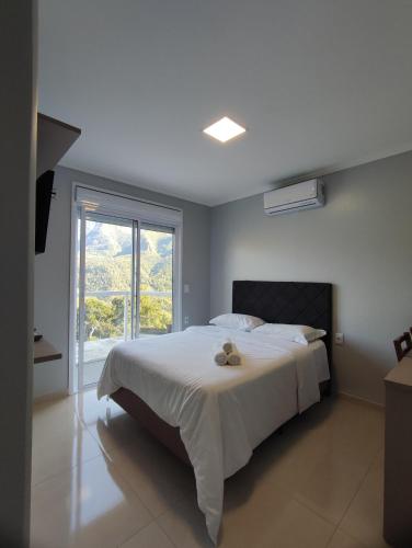 a bedroom with a large white bed with a window at Hotel Du Rastro in Louro Müller