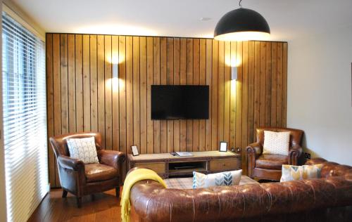 a living room with a couch and two chairs and a television at The Lawrance Luxury Aparthotel - York in York