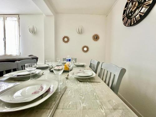une salle à manger avec une table avec des assiettes et des verres à vin dans l'établissement L'Évêché lumineux et zen, à Limoges