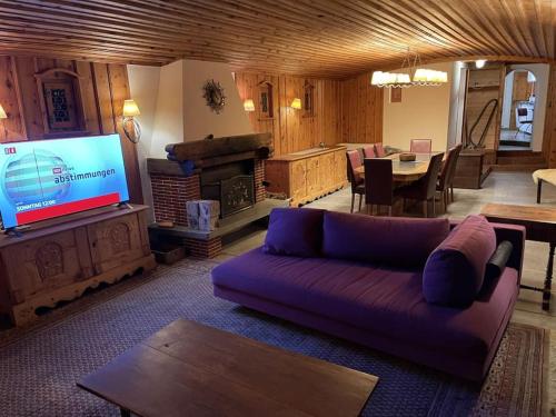 a living room with a purple couch and a tv at Ski In&Out, Lenzerheide freistehendes Top CHALET, urchig, gross in Valbella