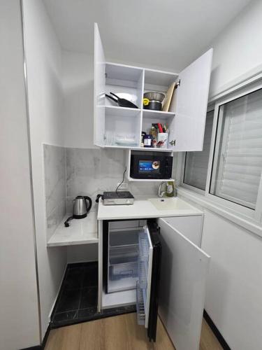 a small kitchen with white cabinets and a desk at Ryo 35 דירת נופש מושלמת מרחק 5 דקות מחוף הים in Bat Yam