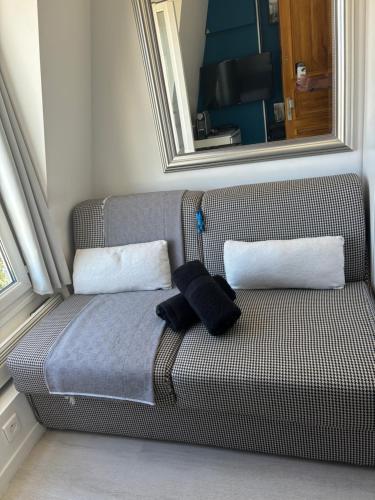 - un canapé avec 2 oreillers blancs et un miroir dans l'établissement Paris 17 - Coeur Batignolles - Beau studio 10 m2 -110 sqf - Etat neuf - Calme - Idéal une personne - single occupancy, à Paris