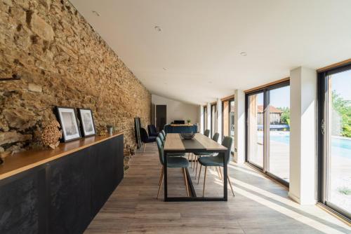 une salle à manger avec un mur en pierre, une table et des chaises dans l'établissement Le Verger : gîte familial avec piscine, à Vivonne