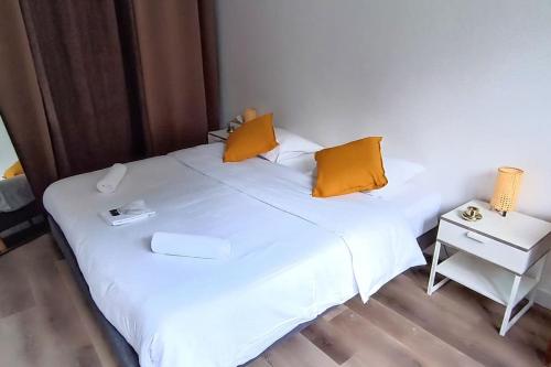 - un lit blanc avec des oreillers orange dans l'établissement Charmant 2 pieces entre Disneyland et Paris avec jardin, à Villiers-sur-Marne