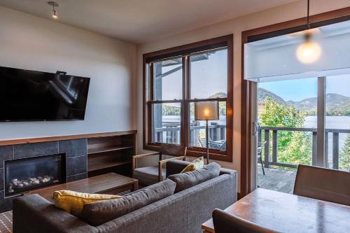 a living room with a couch and a fireplace at Lakefront Mountain View - Resort Loft in Lac-Superieur
