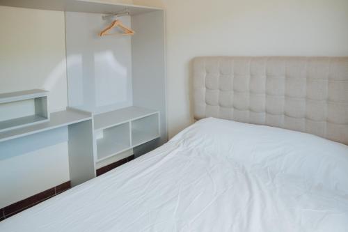 a bedroom with a white bed and a white headboard at Las Loicas Tempo in Esquel