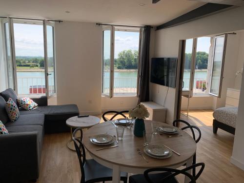 un soggiorno con un tavolo e un divano di Appartement neuf, vue sur saône a Mâcon